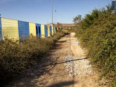 Posteggiamo la macchina nell'area antistante la fabbrica e ci incamminiamo lungo uno stretto sentiero sterrato che costeggia la ferrovia, fino a raggiungere dei campi compresi fra due cavalcavia